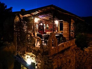 A rustic stone building with a covered patio area, stone walls, and a wooden pergola. - Dana Tower Hotel  (Dana)