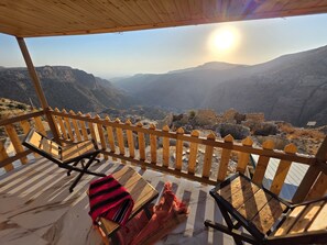 A wooden deck with chairs and a blanket, overlooking a mountainous landscape. - Dana Tower Hotel  (Dana)