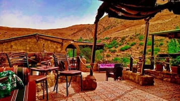 Outdoor seating area with stone walls and terracotta flooring, offering a range of seating options.