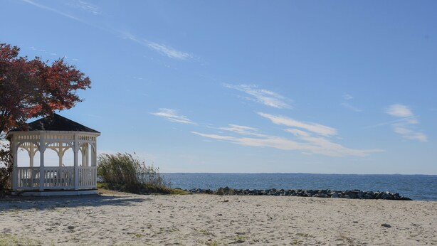 Ein Kiosk an einem sandigen Strand mit freiem Blick auf das Meer und eine felsige Küste.