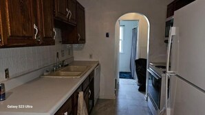 A kitchen with wooden cabinets, a white countertop, and a refrigerator. - Get More Bang For Your Buck! (Wichita)
