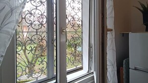 Een kamer met een raam, voorzien van decoratieve metalen spijlen en uitzicht op een tuin.