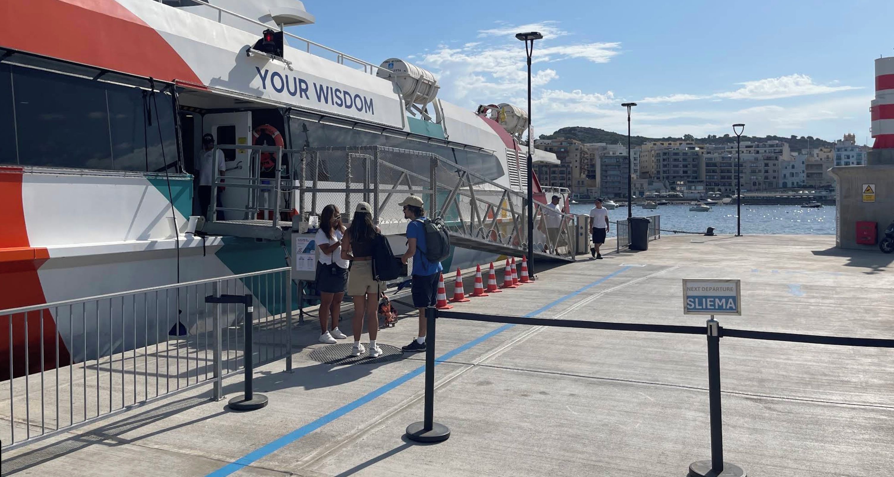 A ferry dock with a sign indicating the next departure to Sliema.