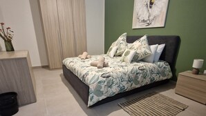 Een slaapkamer met een bed, nachtkastje, kledingkast, een aan de muur hangend schilderij en een vloerlamp.