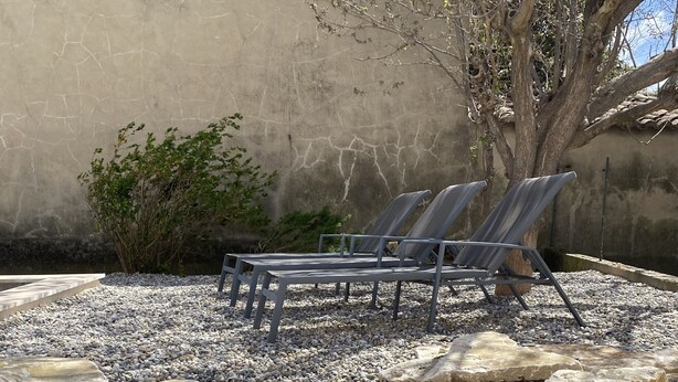 A patio area with two lounge chairs, a large tree, and a stone wall. - Gîtes Chez Prune Entièrement Rénové Avec Piscine Privée (Rasteau)