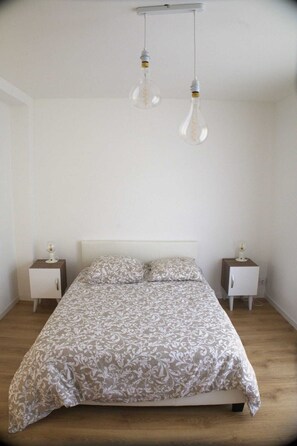 Une chambre à coucher avec un lit, deux tables de chevet et deux luminaires suspendus.