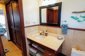 Ein Badezimmer mit Waschbecken, Spiegel, Handtuchhalter und Toilette.