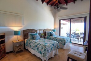 Ein Schlafzimmer mit zwei Betten, einem Deckenventilator und Blick auf die Terrasse.