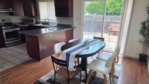 A kitchen with a central island, dining table with chairs, and a view of the backyard through a sliding glass door. - Beautiful, spacious 3 bedroom Napa Adjacent hideaway. Pet and family friendly  (American Canyon)