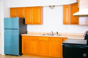 Una cocina con armarios de madera, un refrigerador azul, un lavamanos y una estufa.