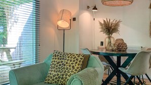 Una sala moderna con un sofá, una mesa de comedor y sillas. Hay una lámpara de pie y un colgador de luces.