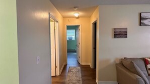 A hallway with a wooden floor, a rug, a couch, and a painting on the wall. - Trail 10 Hideaway, Entire Apartment in Freeman, WV (Bramwell)