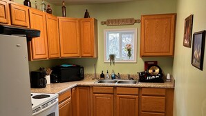 A kitchen with wooden cabinets, a white refrigerator, a stove, a microwave, and a sink. - Trail 10 Hideaway, Entire Apartment in Freeman, WV (Bramwell)