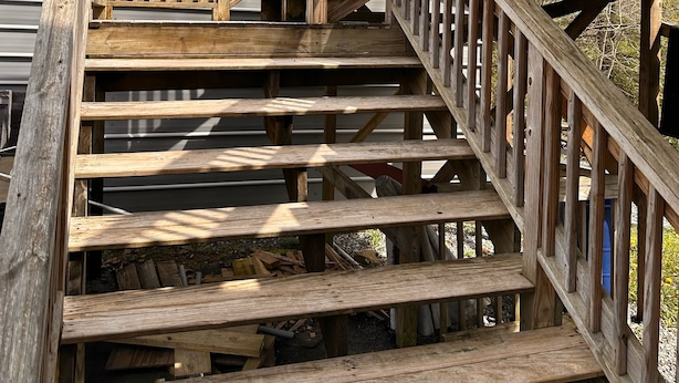 A wooden staircase with a metal railing, leading to a building with a green roof. - Trail 10 Hideaway, Entire Apartment in Freeman, WV (Bramwell)