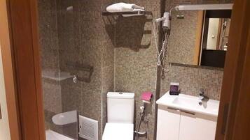 Une salle de bain avec douche, toilettes et lavabo.