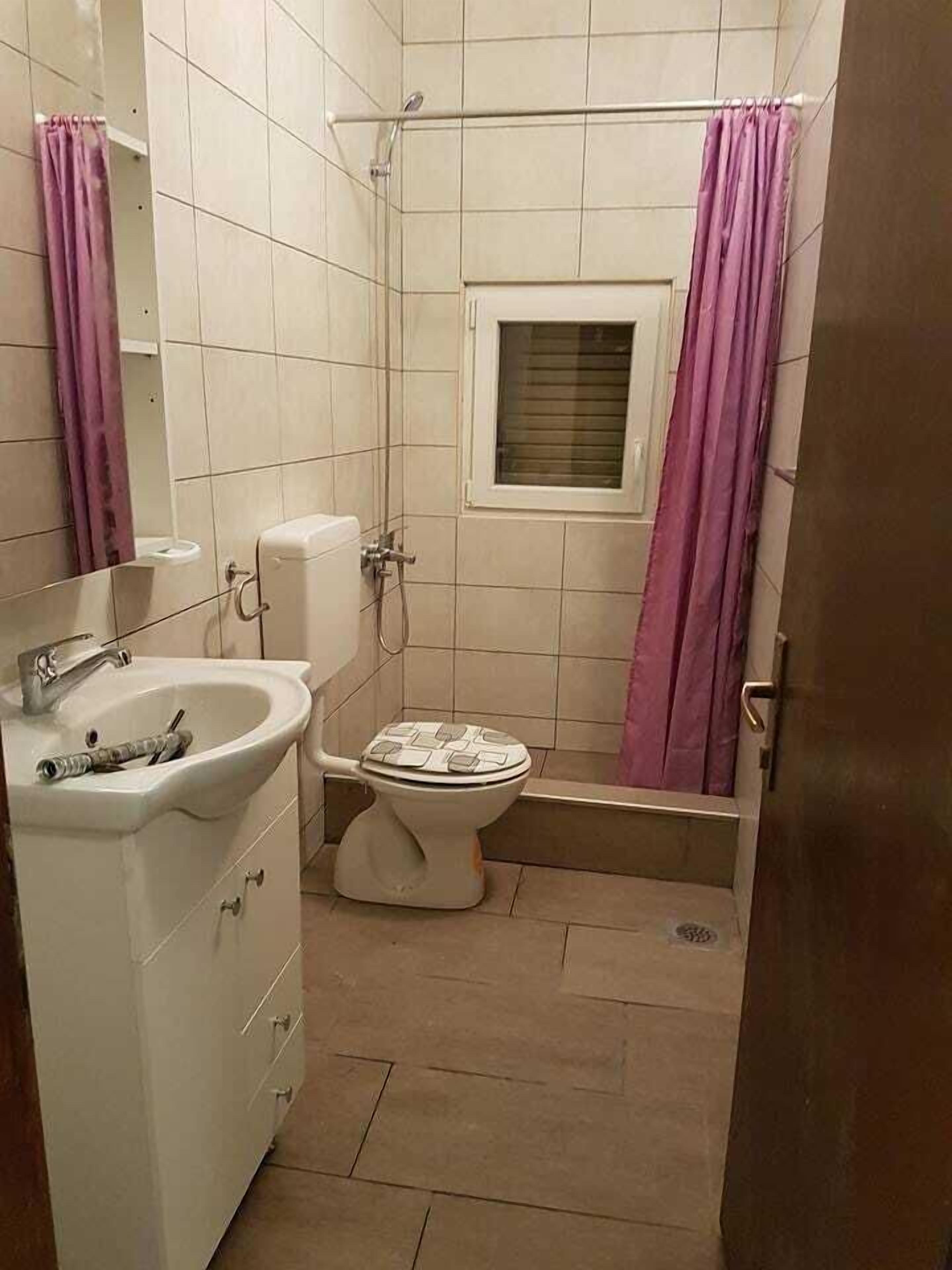 A small bathroom with a toilet, sink, and shower.