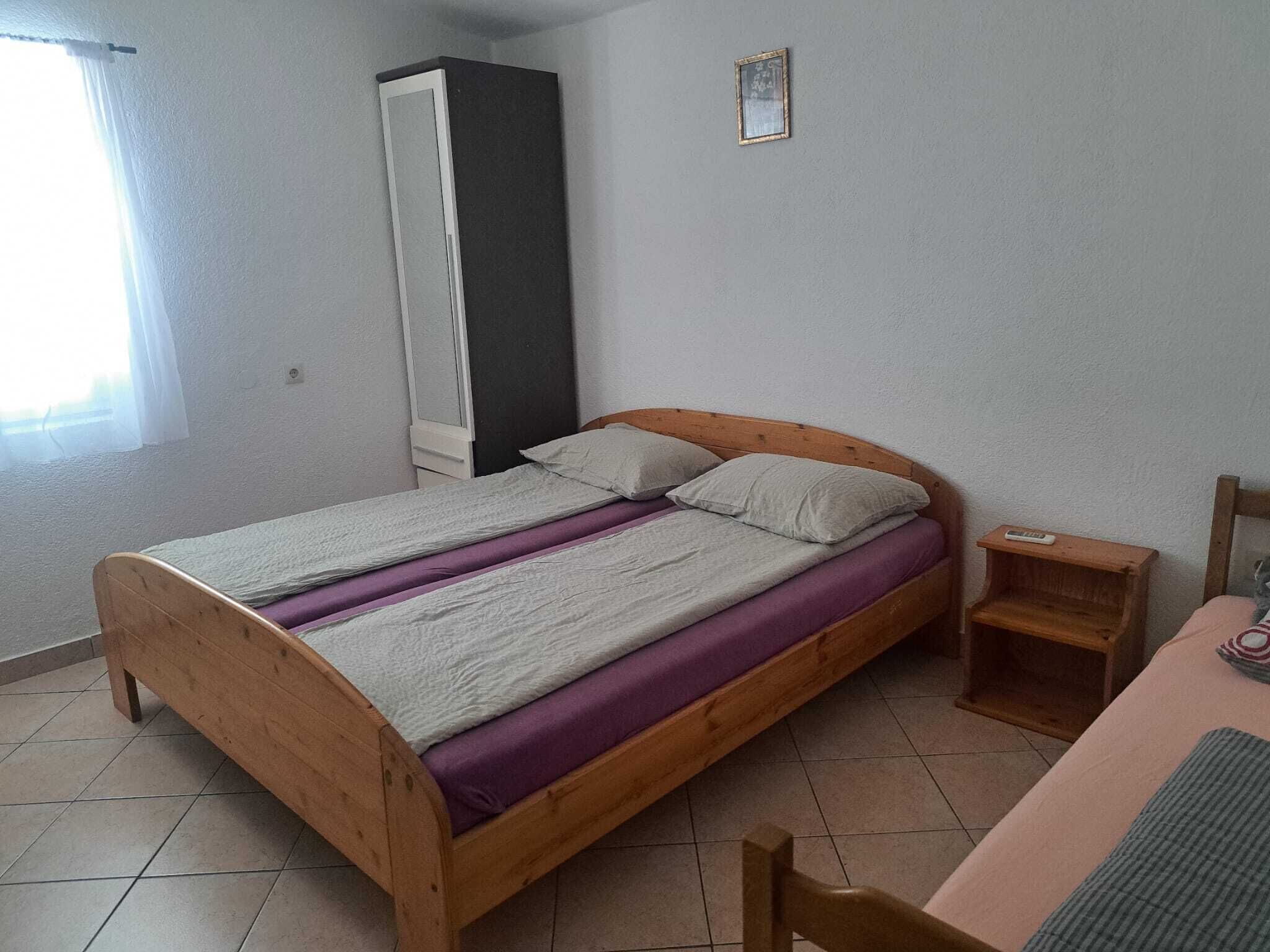 Un lit simple avec un cadre en bois, une petite table de chevet et une chaise.
