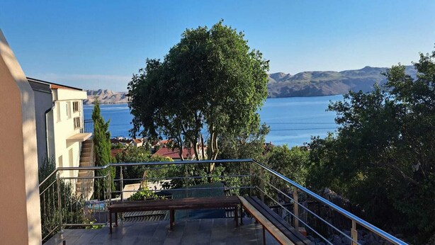 Un balcón con vista a un cuerpo de agua y montañas al lejano.