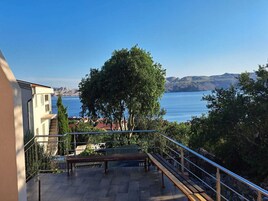 Un balcón con vista a un cuerpo de agua y montañas al lejano.