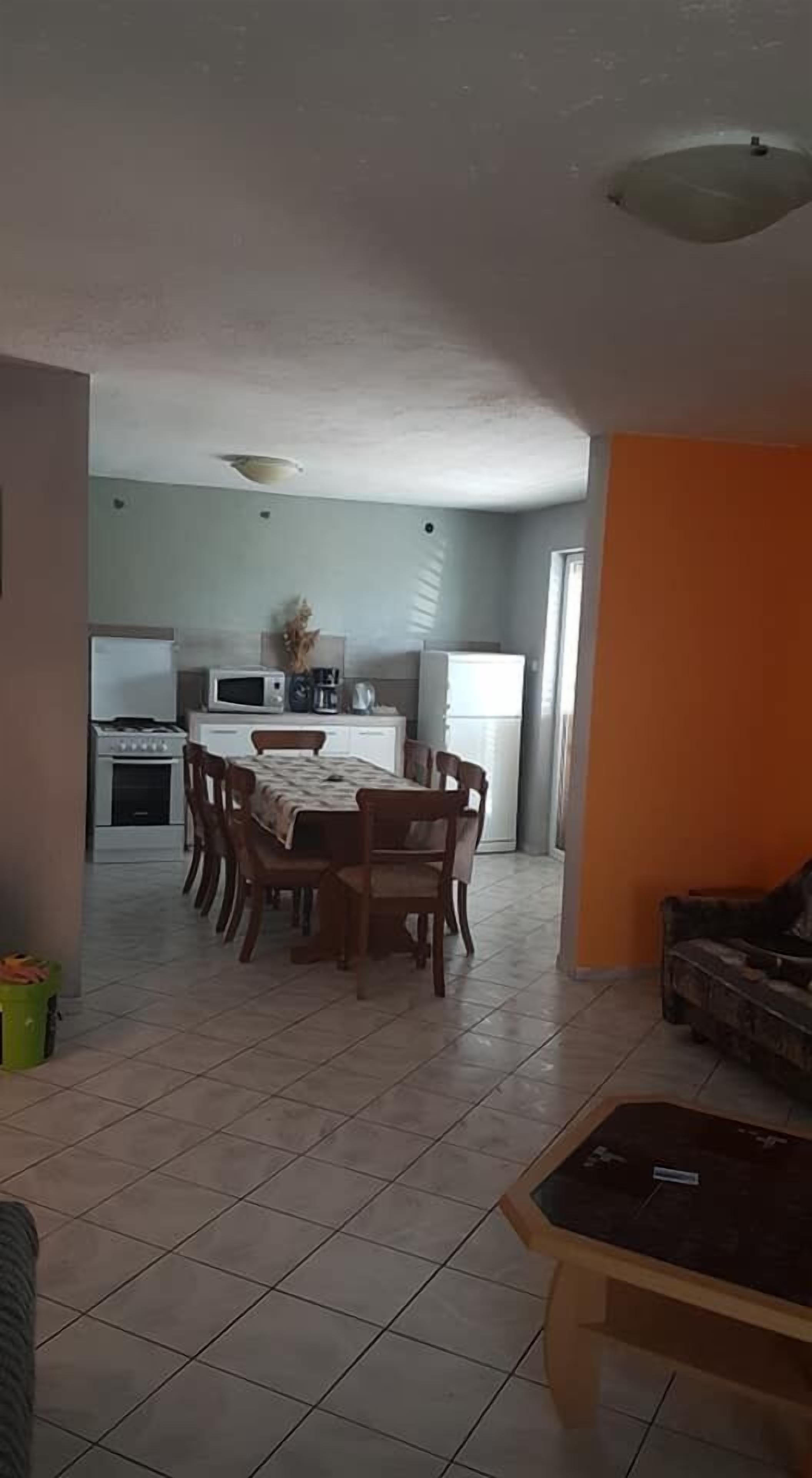 Un comedor con mesa y sillas, una cocina al fondo y una sala de estar con sofá.