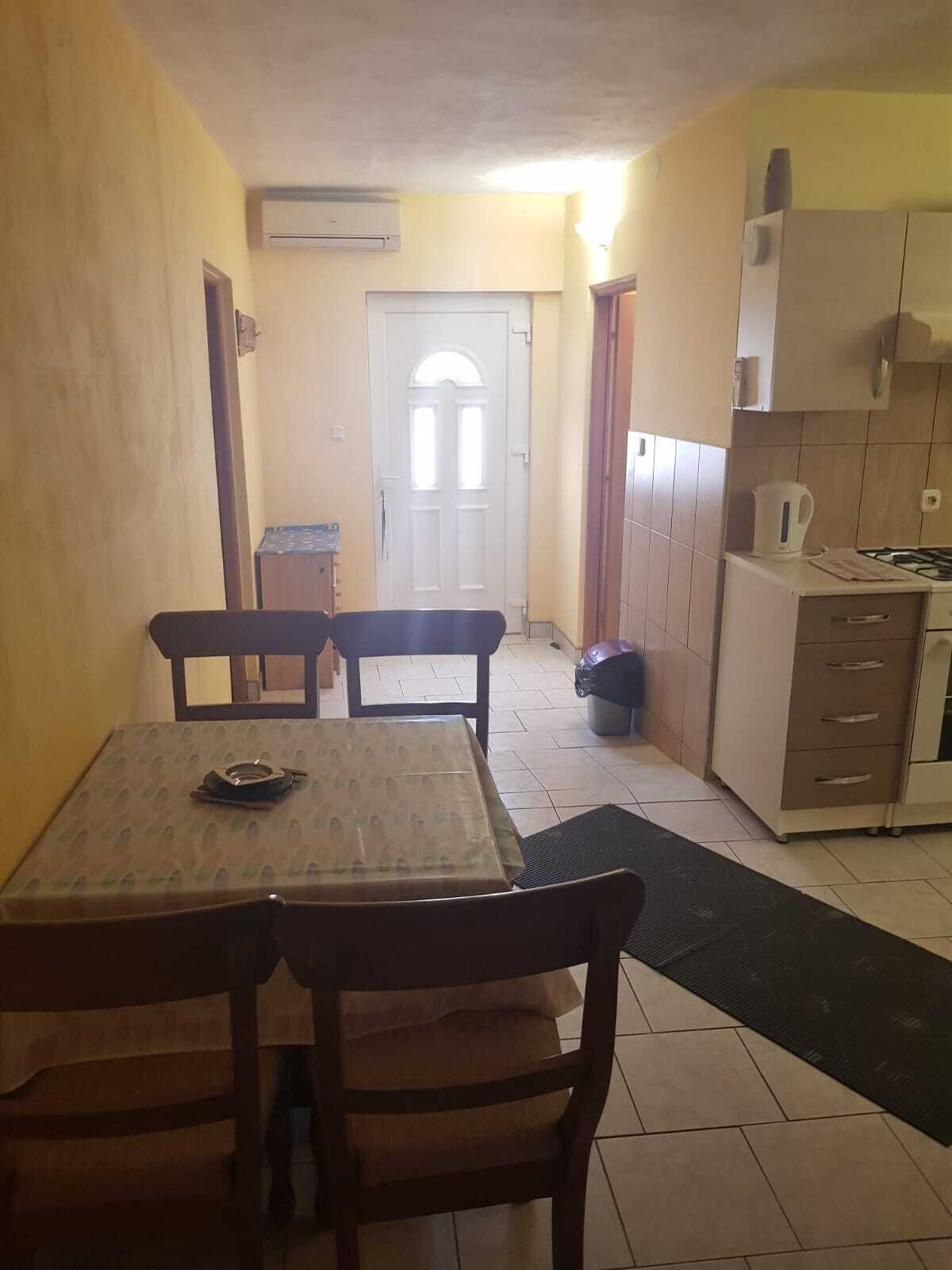 Une cuisine compacte avec un coin repas, dotée d’un sol carrelé, d’une petite table avec des chaises, d’une cuisinière et de placards.