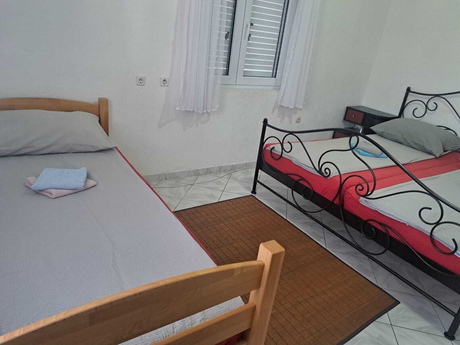 A single bed with a wooden headboard and a metal frame bed with a red and white bedspread.