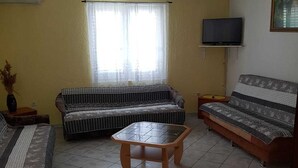 Una sala de estar con sofá, una mesa de centro, televisor y un cuadro en la pared.
