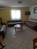Una sala de estar con sofá, una mesa de centro, televisor y un cuadro en la pared.