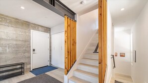 A modern interior with a concrete wall, a wooden staircase, and a white door.
