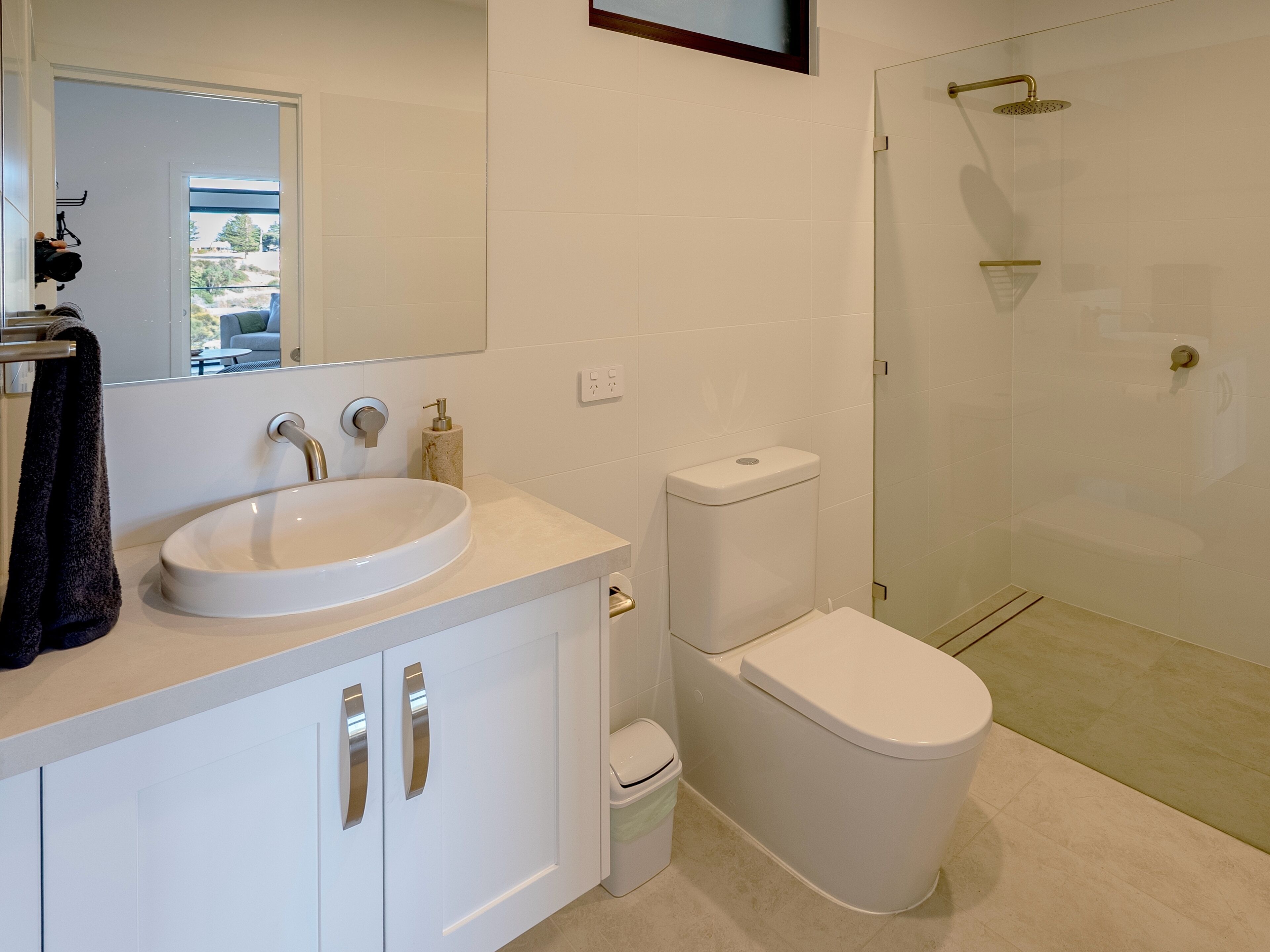Une salle de bain moderne avec un lavabo, des toilettes et une douche, le tout de couleur blanche.