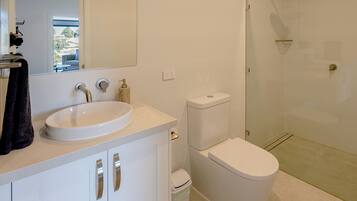 Une salle de bain moderne avec un lavabo, des toilettes et une douche, le tout de couleur blanche.