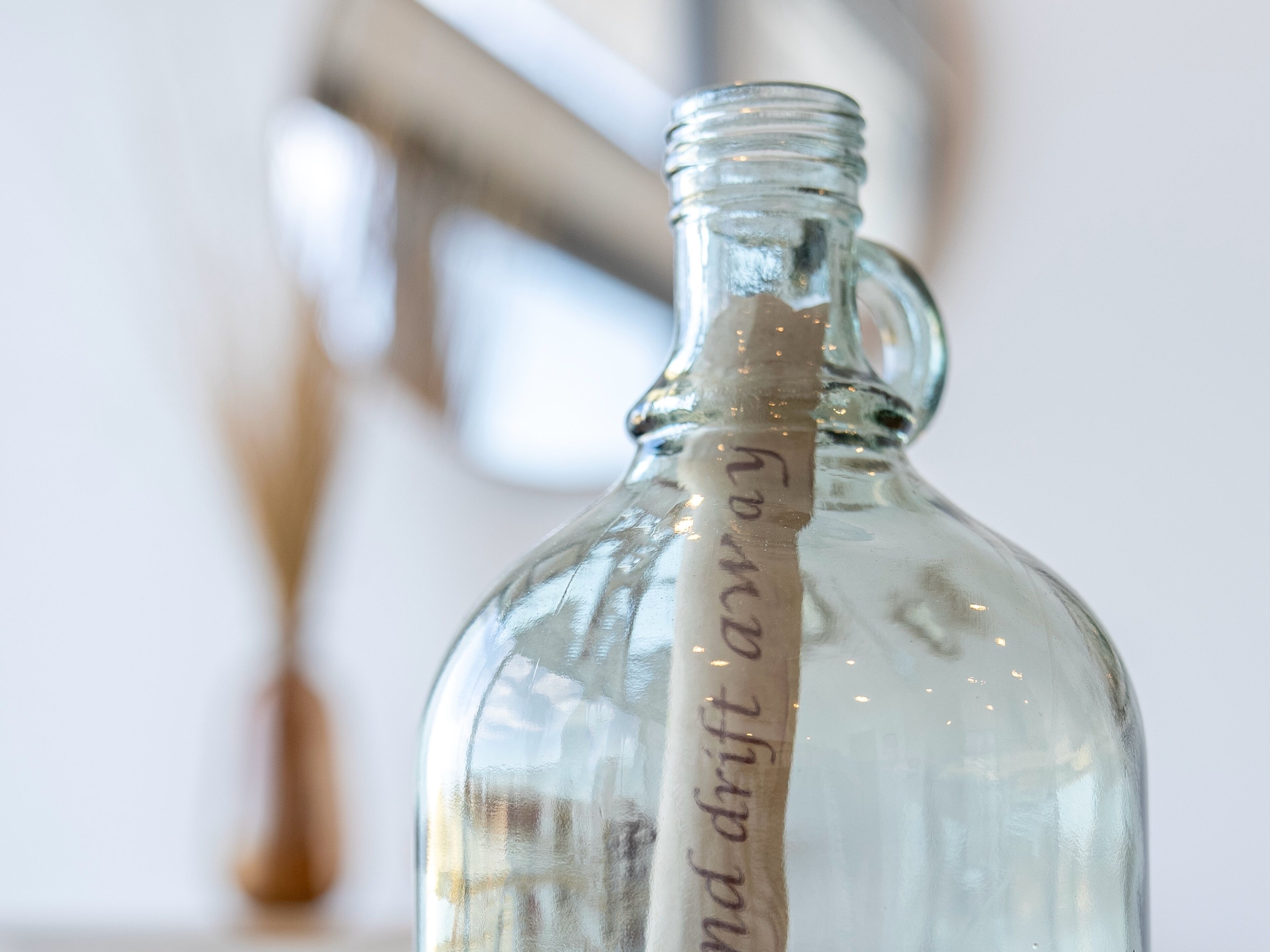 Une bouteille en verre transparent, à col étroit et dotée d’une anse, contenant un liquide.