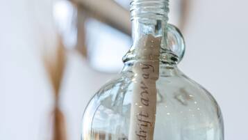 Une bouteille en verre transparent, à col étroit et dotée d’une anse, contenant un liquide.