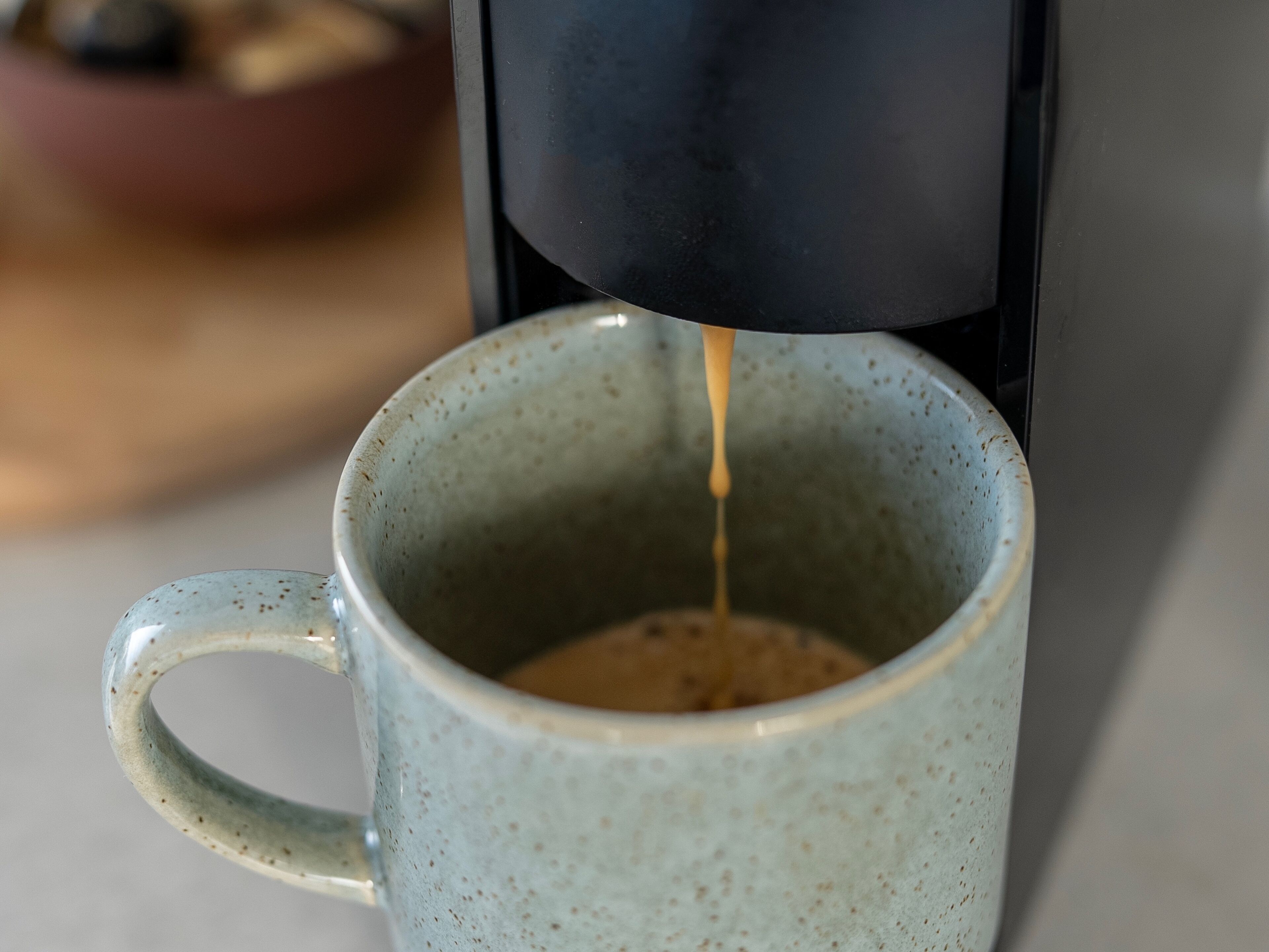 Primer plano de una cafetera sirviendo café en una taza de cerámica.