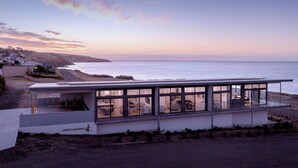 A modern coastal building with large windows offering ocean views, a flat roof, and a sign indicating 'COVE LANDING'. - Cove Landing Ocean View Apt-01 Karatta Sleeps 4 (Penneshaw)