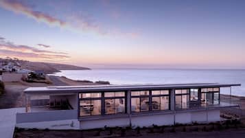 Un edificio moderno frente al mar, con amplios ventanales que ofrecen vistas al océano, techo plano y un cartel que indica 'COVE LANDING'.