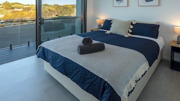 Un dormitorio moderno con una cama grande, un balcón y dos cuadros enmarcados en la pared.