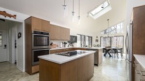 Une cuisine moderne dotée d’un îlot central, d’appareils électroménagers intégrés et d’un coin repas offrant une vue agréable.