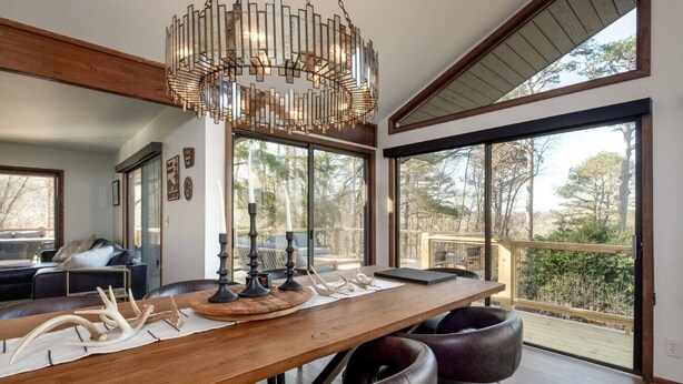 Un espace de repas moderne avec une table en bois, des chaises en cuir et un lustre original.