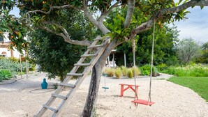 A tree with a wooden ladder, a swing set, and a garden with various plants. - Quinta da Janela Azul - Limão (Tavira)