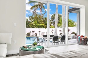 A modern living room with a large sliding glass door leading to a pool area.