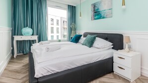 A bedroom with a bed, bedside table, nightstand, and a window with curtains. - Golden Azzure by Grand Apartments (Gdansk)