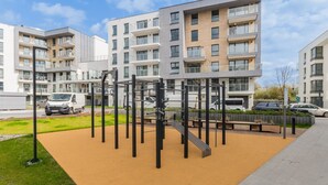 A modern apartment building with multiple balconies and a playground area with exercise equipment. - Golden Azzure by Grand Apartments (Gdansk)