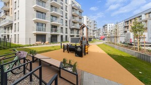 A modern apartment complex with a playground, outdoor seating, and a bike rack. - Golden Azzure by Grand Apartments (Gdansk)
