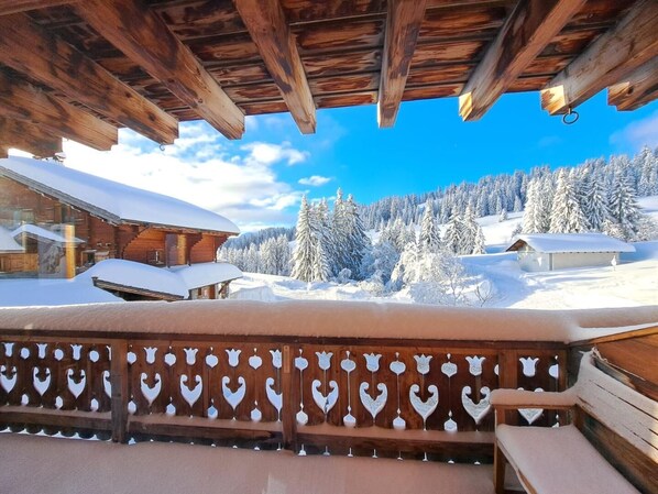 A wooden cabin with a balcony overlooking a snowy landscape.