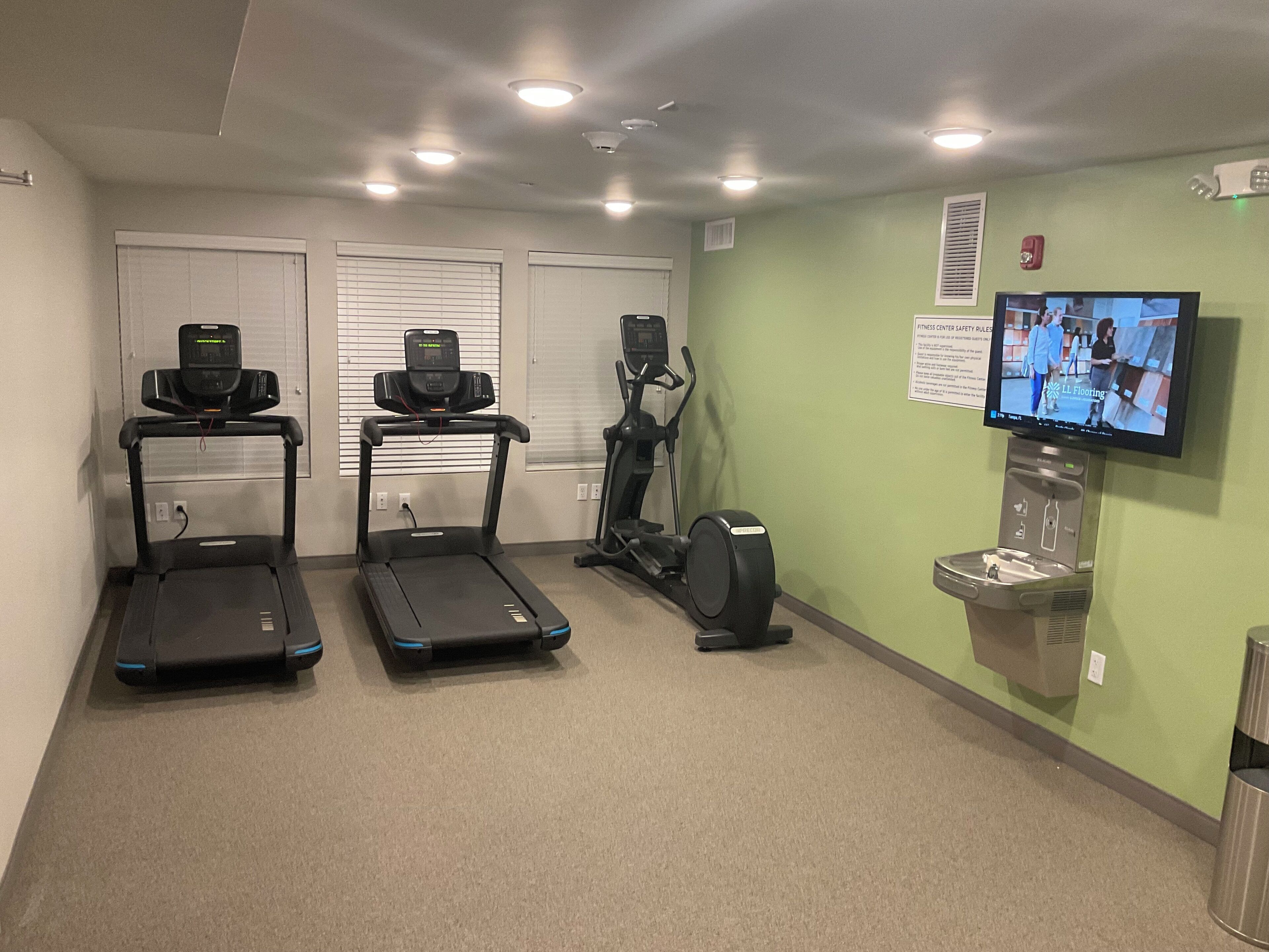 A fitness center with treadmills, an elliptical, and a television displaying a fitness program.