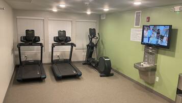 A fitness center with treadmills, an elliptical, and a television displaying a fitness program.