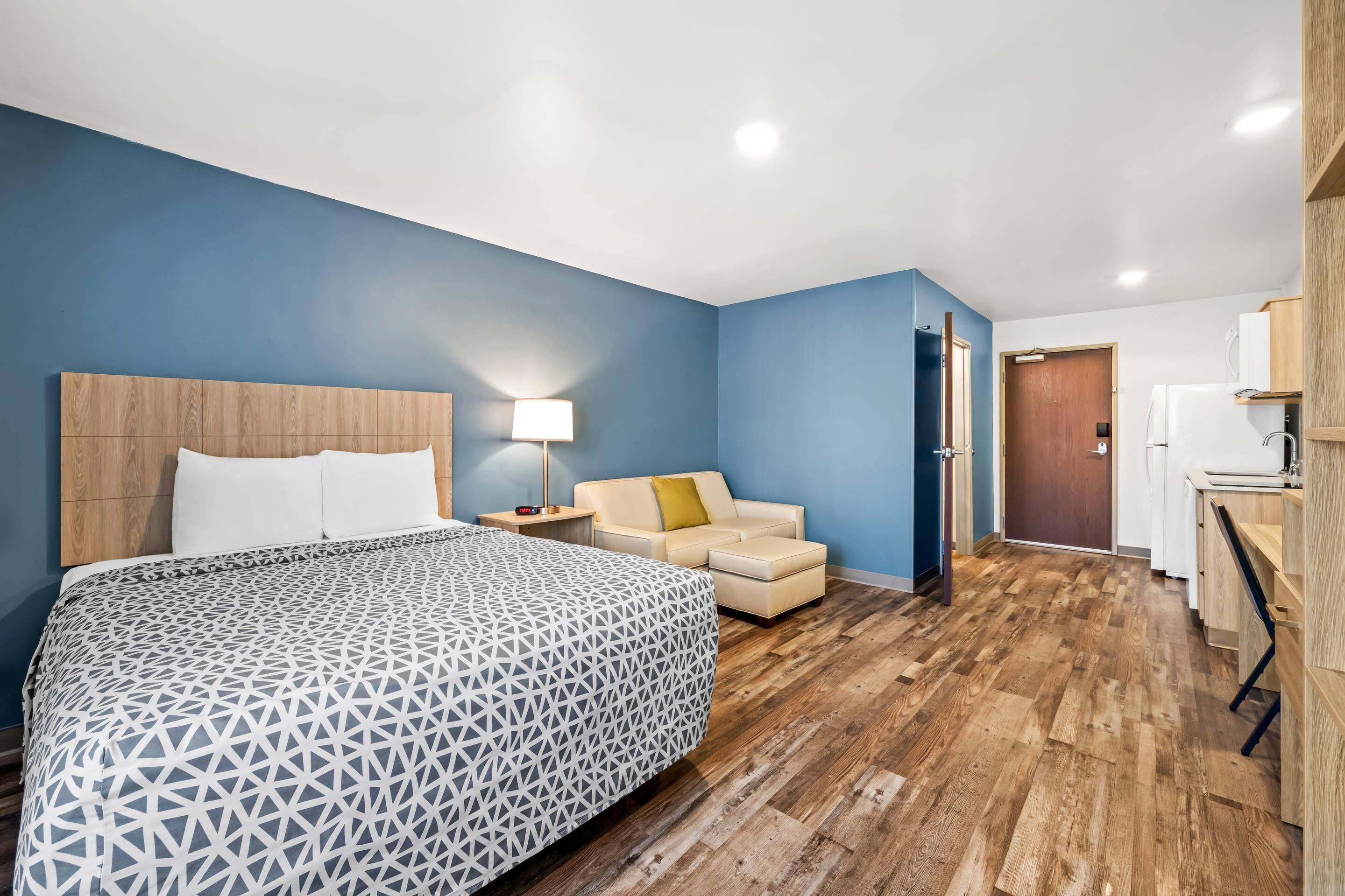 A hotel room with a large bed, a sofa, a desk, and a bathroom.