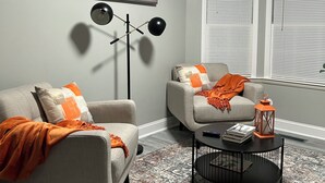 Un salon avec deux canapés, une table basse, un lampadaire et un tableau accroché au mur.