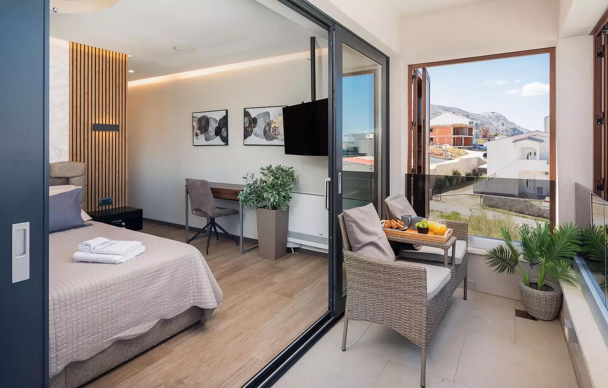 A modern hotel room with a balcony, a bed, a desk, and a chair.